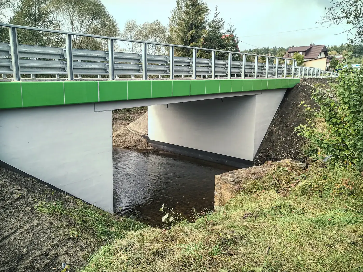 Most drogowy nad ciekiem, zielone panele boczne i bariera ochronna